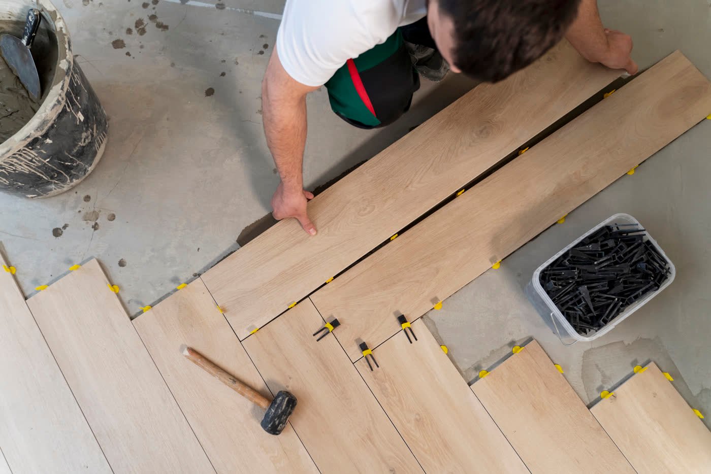 Handwerker verlegt Holzdielen / Parkett